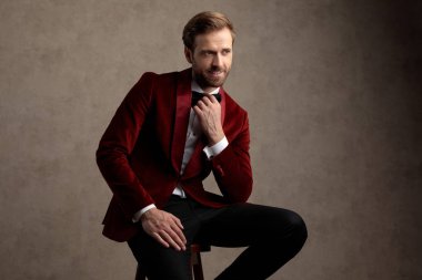 Yakışıklı damat papyonunu düzeltiyor ve gülümsüyor.