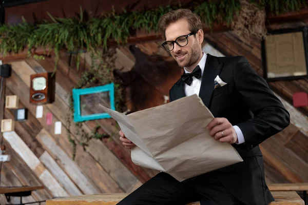 Positive groom reading a newspaper while wearing glasses — 스톡 사진