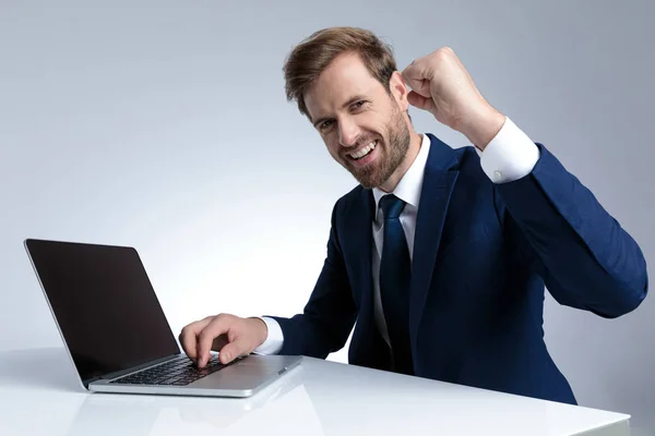 Positive businessman celebrating and writing on his laptop — ストック写真