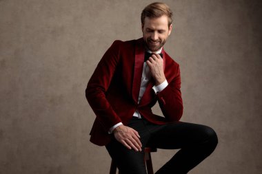 Neşeli, zarif bir adam papyonunu ayarlıyor ve gülüyor.