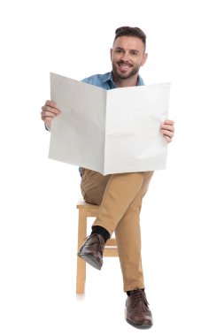 Mutlu genç adam gülümsüyor ve elinde gazete tutuyor.