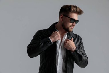 Deri ceketli seksi genç adam poz veriyor.