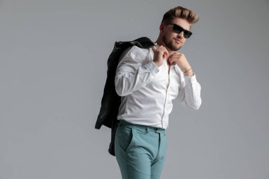 Deri ceket giyen ve gömleğini düzelten seksi adam.