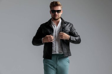 Deri ceket ve güneş gözlüğü takan seksi manken.