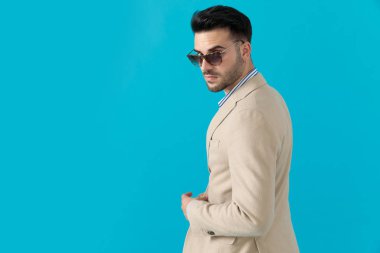 Dramatik havalı adam güneş gözlüğü takıyor ve arkasını kolluyor.