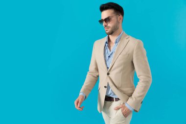 Güneş gözlüğü takan ve yürüyen kendine güvenen genç adam.