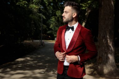 İş adamı ceketini kapatıyor ve ciddi bakıyor.