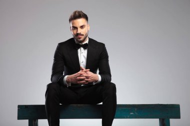 Yakışıklı damat ellerini tutuyor ve gülümsüyor.