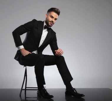 Yakışıklı damat gülümsüyor ve bacaklarına yaslanıyor.