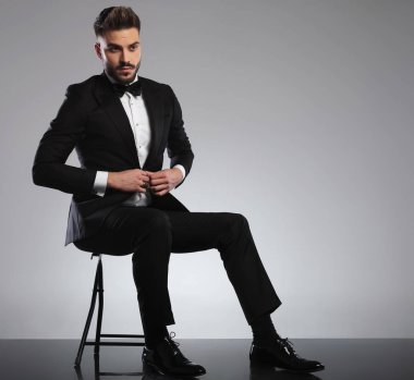 Gergin model gömleğinin düğmelerini açıp başka yere bakıyor. 