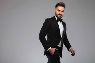 Damat elini cebine koyup gülümsüyor.