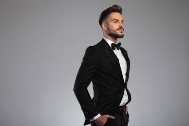 Kibirli genç damat ellerini cebinde tutuyor. 