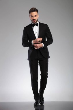 Smokin giyerken manşetini ayarlayan kararlı genç bir manken.