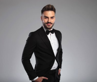 Kendine güvenen bir model ellerini cebinde tutuyor ve gülümsüyor.