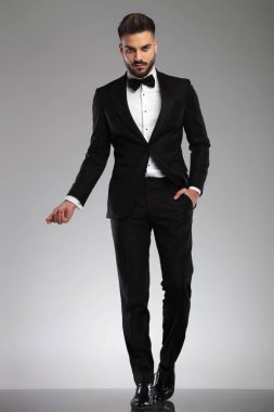 Ciddi genç manken yürürken parmaklarını şıklatıyor.