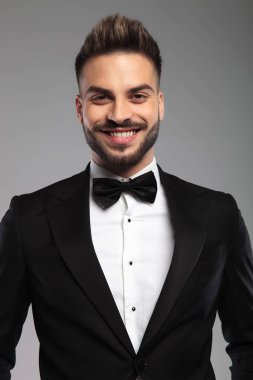 Smokin giyerken gülümseyen neşeli damat.