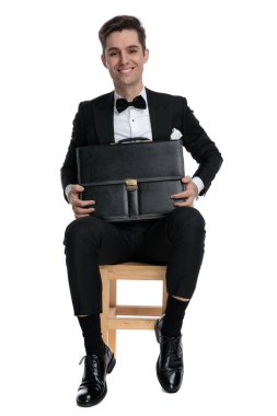 Mutlu genç model bavulu tutuyor ve gülümsüyor.