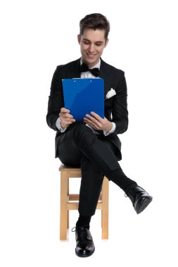 Gülümseyen genç moda adamı elinde tuttuğu ve okuduğu panodan