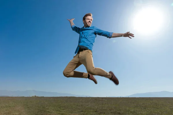 Casual man wearing blue shirt jumping high to the sky — Stock Photo, Image