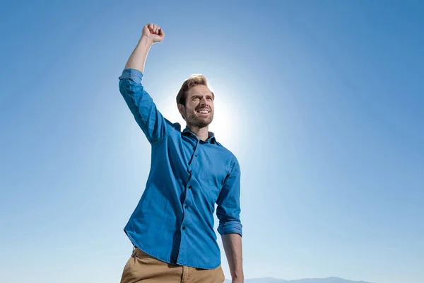 Hombre casual de pie y celebrando éxitos con el puño en alto — Foto de Stock