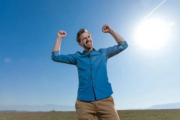 Hombre casual de pie con los puños en alto y mirando hacia otro lado feliz — Foto de Stock