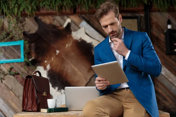 Bothered businessman reading from his tablet and frowning — Stock Photo, Image