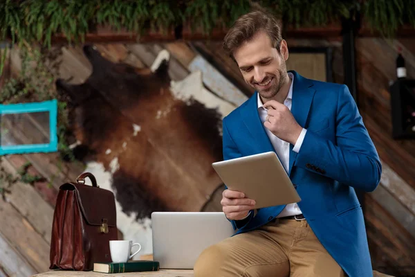 Positieve zakenman lachend vanaf zijn tablet — Stockfoto