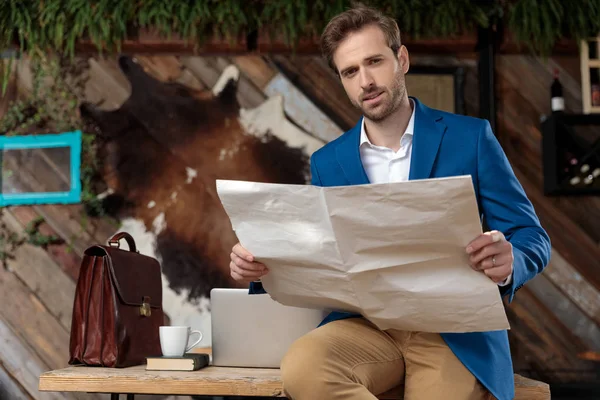 Confident businessman holding a newspaper and looking forward — Stock Photo, Image
