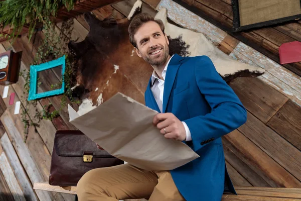 Fröhlicher Geschäftsmann hält eine Zeitung in der Hand und lächelt — Stockfoto