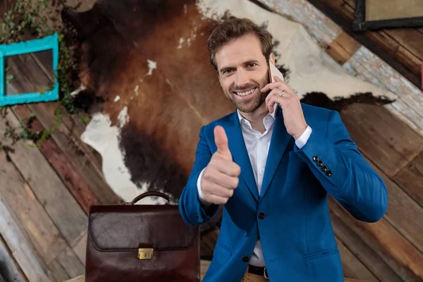 Vrolijke zakenman geeft een duim op, praat op zijn telefoon — Stockfoto