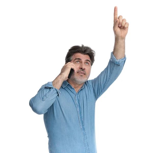 Hombre casual ansioso hablando por su teléfono y apuntando hacia arriba — Foto de Stock