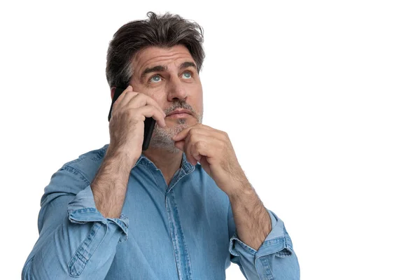 Zamyšlený ležérní muž mluví po telefonu, dívá se nahoru — Stock fotografie