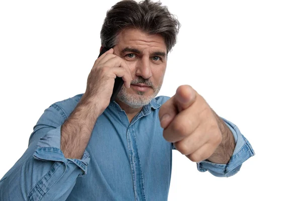 Hombre casual de confianza hablando por su teléfono y apuntando hacia adelante — Foto de Stock