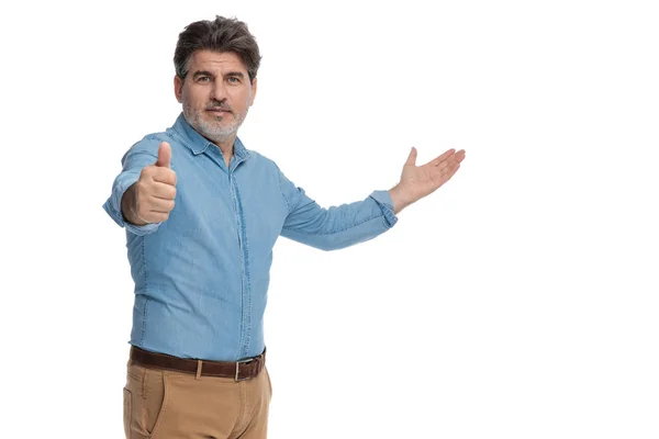 Positieve casual man presenteren en het geven van een duim omhoog — Stockfoto