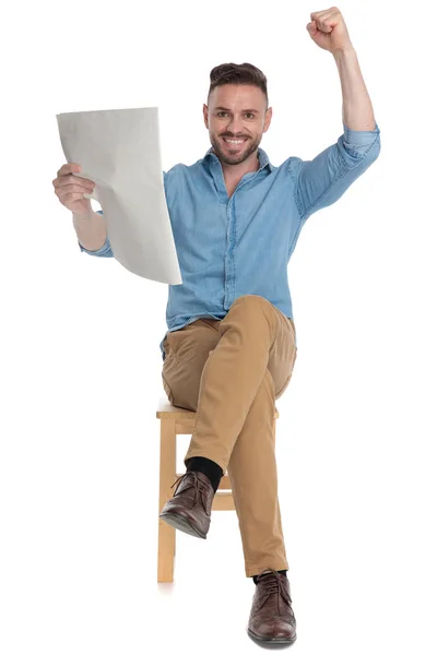 Glücklicher junger Mann hält Zeitung in der Hand und feiert — Stockfoto