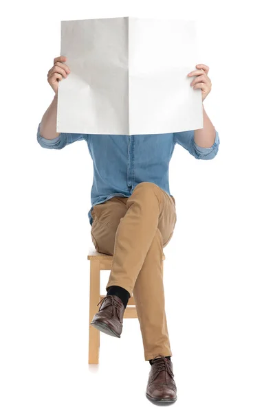 Młody człowiek ukrywa się za gazetą — Zdjęcie stockowe