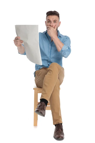 Sorprendido joven leyendo el periódico y cubriendo la boca — Foto de Stock