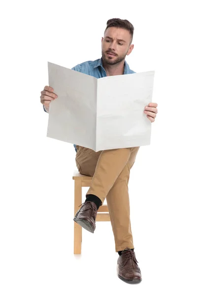 Jovem homem casual segurando e lendo jornal — Fotografia de Stock