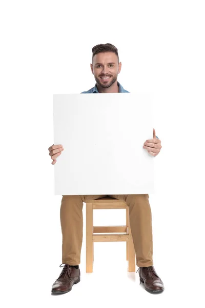 Happy young casual man holding empty board — 스톡 사진