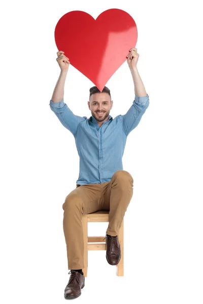 Mladý ležérní muž drží velké červené srdce nad hlavou — Stock fotografie