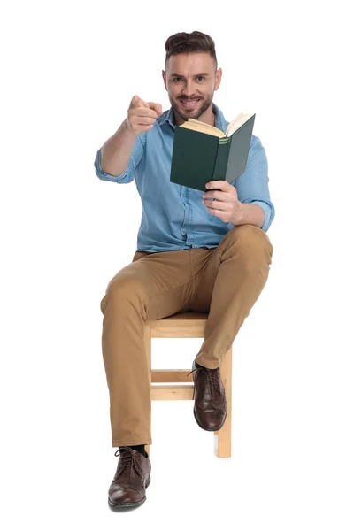Genç, sıradan bir adamın elinde kitap tutması ve işaret etmesi. — Stok fotoğraf