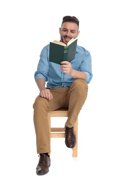 Glücklicher junger Mann lächelt und liest ein Buch — Stockfoto