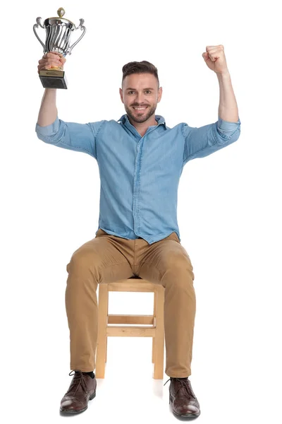 Heyecanlı genç adam elinde kupa tutuyor ve kutluyor — Stok fotoğraf