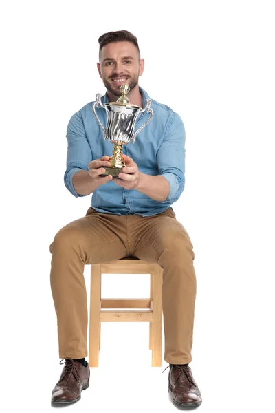 Usmívající se mladý ležérní muž drží trofej — Stock fotografie
