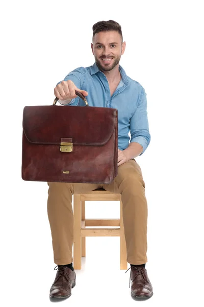 Giovane uomo casual che sorride e tiene in mano la valigia — Foto Stock