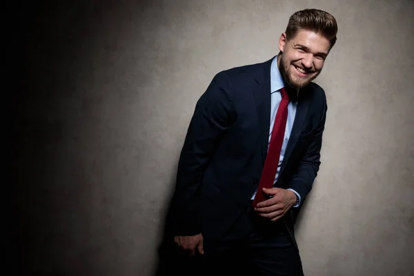 Bonito formal homem vestindo marinha terno de pé e rindo — Fotografia de Stock