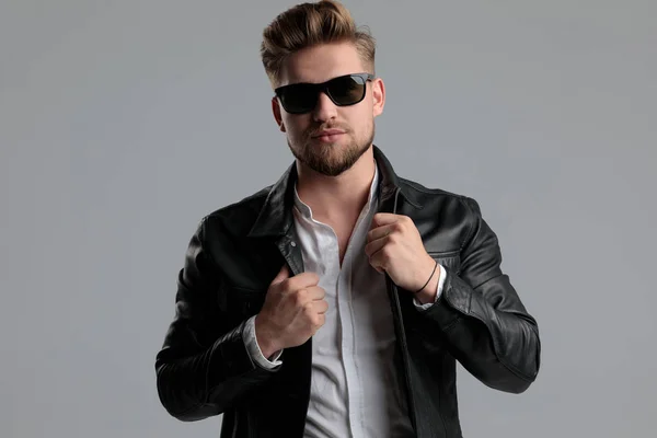 Young handsome fashion model pulling leather jacket — Stock Photo, Image