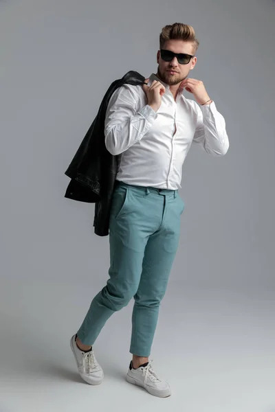 Sexy legal cara arranjando camisa e segurando jaqueta de couro — Fotografia de Stock