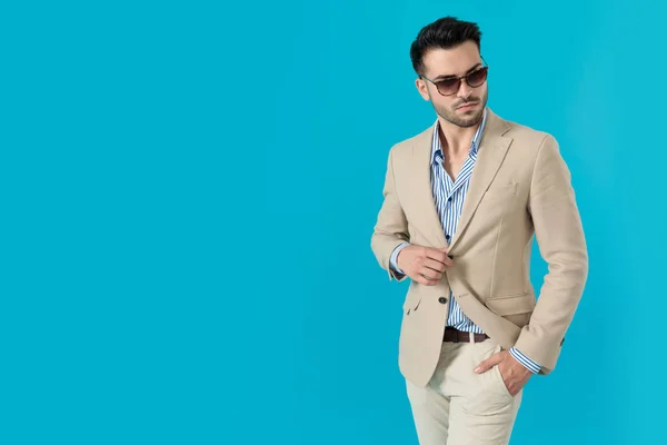 Confident young man wearing sunglasses and adjusting coat — Stock Photo, Image