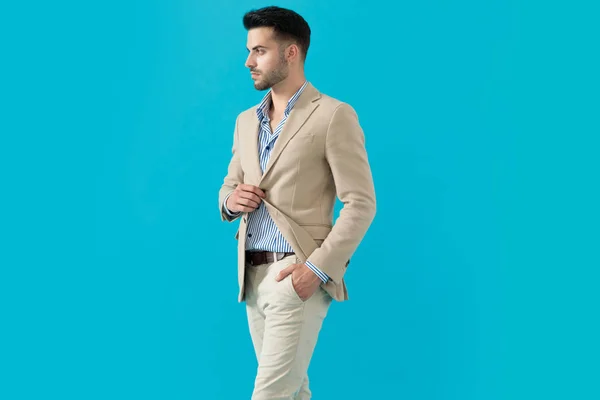 Cool fashion man adjusting coat and looking to side — Stock Photo, Image